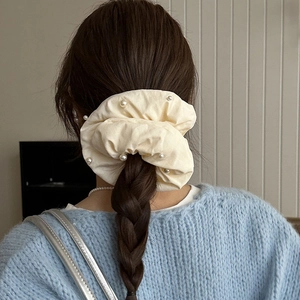 Détail d'un chouchou crème orné de perles sur une coiffure en chignon flou