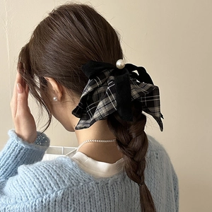 Close-up of velvet plaid bow hair tie with a large pearl detail on a braided hairstyle