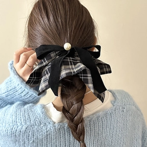 Detail of velvet and plaid bow hair tie with pearl accent on braided hair