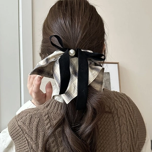Detail view of a plaid velvet bow hair scrunchie with a large white pearl embellishment