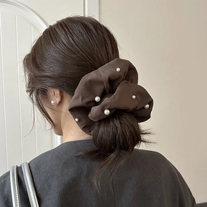 Chouchou élégant en velours marron foncé avec perles blanches sur un chignon haut