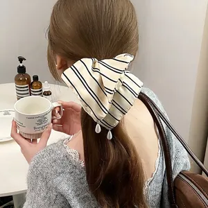 Elegant striped satin bow hair clip with pearl pendants shown on a model's hair