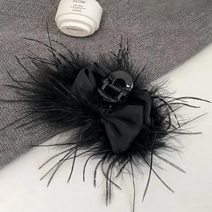 Detail of a black faux ostrich feather hair claw clip with a satin ribbon bow
