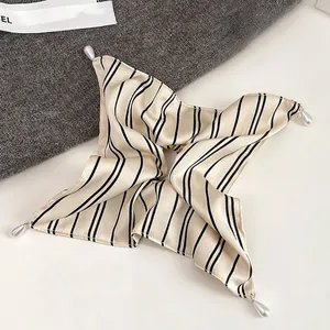 Detail of striped satin scrunchie with elegant pearlescent drop charms and silk texture