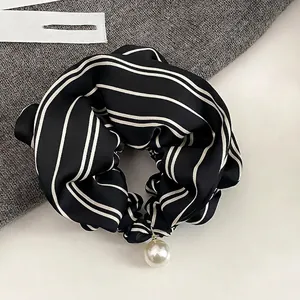 Detailed view of black and white striped satin scrunchie with a large pearl pendant accessory