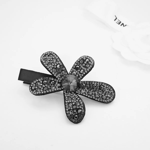 Close-up of a luxury flower hair clip featuring black gradient rhinestones and silk texture