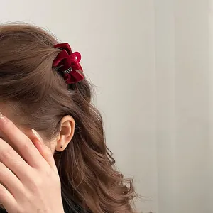 Close-up of a burgundy velvet bow hair clip with sparkling rhinestones on model's hair