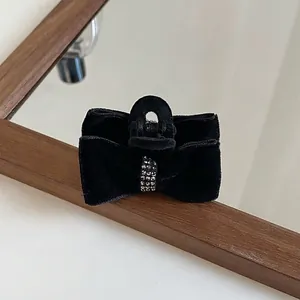 Detailed view of a black velvet bow hair claw clip with shimmering crystal embellishments