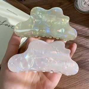 Macro detail of large iridescent shark hair clips with a pearlescent finish and wave design
