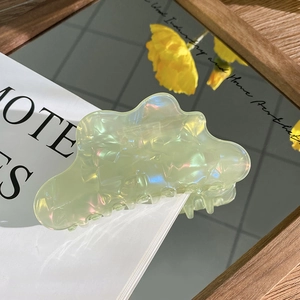Close-up of cloud-shaped light green hair claw with aurora iridescent finish on magazine