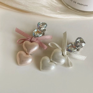 Close-up of pink and white pearlescent heart hair clips with crystals and silk ribbon