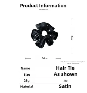 Detail of 14cm black polka dot satin hair scrunchie with smooth fabric texture
