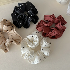 Close-up of four pleated polka dot satin scrunchies in black, red, beige and white colors