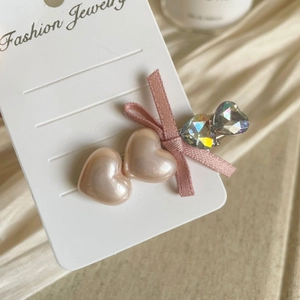 Detail of pink bow hair clip with heart pearls and sparkling rhinestones on satin