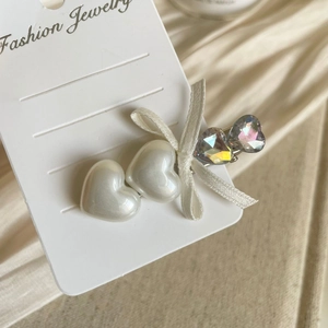 Close-up of bow and heart rhinestone hair clip with pearls on elegant satin background