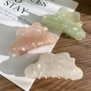 Close-up of cloud-shaped iridescent hair claws in pastel green, pink, and pearl white