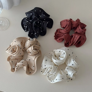 Close-up of four satin polka dot hair scrunchies in black, brown, cream and champagne
