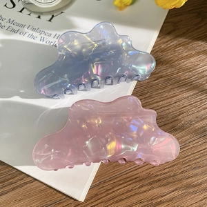 Iridescent cloud-shaped hair claw clips in blue and pink set for women on a desk