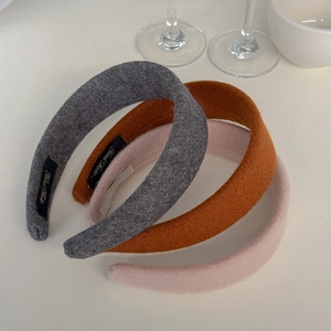 Three thick wool blend headbands in grey, brown, and pink with a handmade label