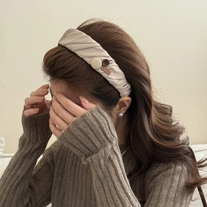 Detail of light brown fabric headband featuring a round button and Hand Made leather tag