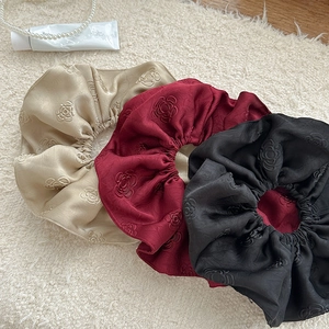 Three jacquard satin scrunchies in beige, red, and black with floral textures