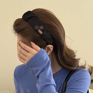 Elegant black pleated fabric headband with button detail and high-top aesthetic style