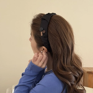 Detailed view of handmade black pleated fabric headband with buttons and square label