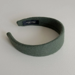 Detail showing the inner handmade label and fuzzy dark green texture of the wide headband