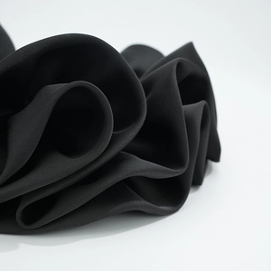 Dettaglio macro dell'elastico per capelli in raso nero con pieghe multistrato