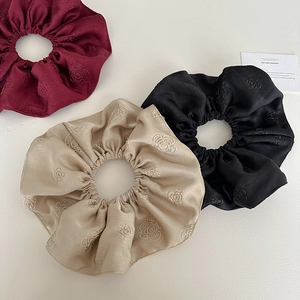 Detailed view of jacquard satin scrunchies in burgundy, champagne and black silk