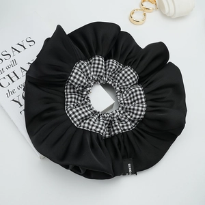 Macro dettaglio dello scrunchie in raso nero e quadretti con etichetta Blind For Love