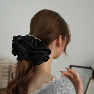 Dettaglio di elastico in raso nero con bordo a quadretti su una coda di cavallo bassa