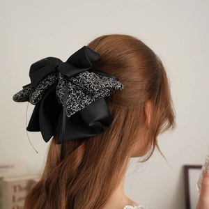 Detail view of large patchwork floral bow hair clip styled on light brown wavy hair