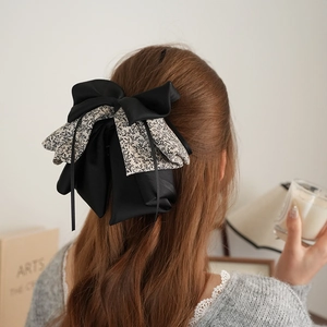 Detail of vintage floral patchwork satin bow hair clip worn as an elegant ponytail clip