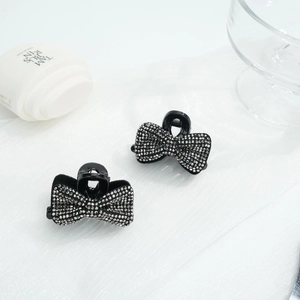 Détail de deux mini pinces à cheveux nśud serties de strass sur tissu blanc