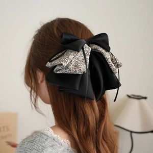 Detail of a large layered floral and black satin bow hair clip worn on long hair