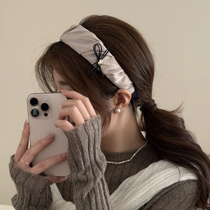 Detail of elegant champagne satin headband featuring a delicate black ribbon bow accent