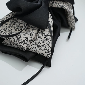 Detail of vintage floral bow hair clip with contrasting black and beige fabric textures