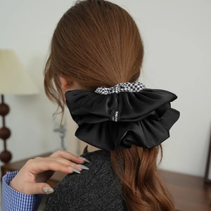 Elegante elastico per capelli in raso nero e quadretti vichy indossato da una donna