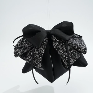 Detailed view of large black satin bow clip with white floral vine print texture