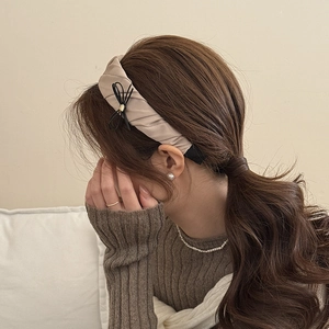 Detail view of smooth pleated satin headband with a delicate black bow and gold bead