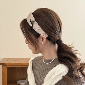 Detail view of apricot pleated headband with black bow knot and metal bead decoration