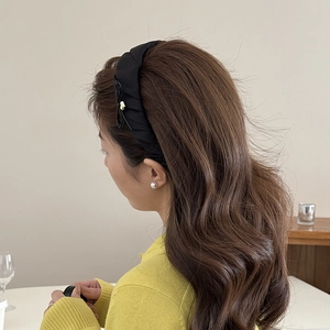 Detail of black pleated satin headband showing texture and thickness on model side view