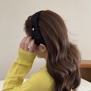 Detail of black pleated fabric headband with small gold metal charm on model