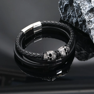 Detail of multi-layer braided leather bracelet with silver skull charms and magnetic clasp
