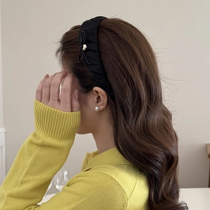 Side view of a black satin padded headband with layered bow and heart charm detail