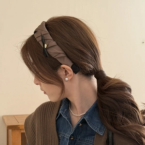 Close-up of brown pleated satin headband with ribbon detail on female model hair