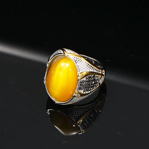 Dettaglio anello vintage con occhio di gatto giallo e incisione floreale complessa