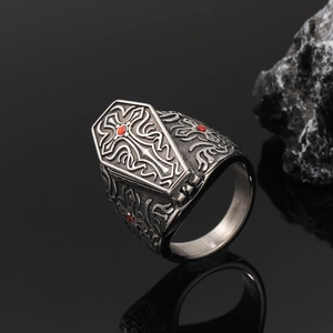 Macro shot of gothic coffin ring with a red gem cross and vintage scroll patterns
