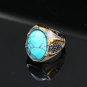 Dettaglio macro di anello da uomo retrò con turchese ovale e accenti punk oro-argento